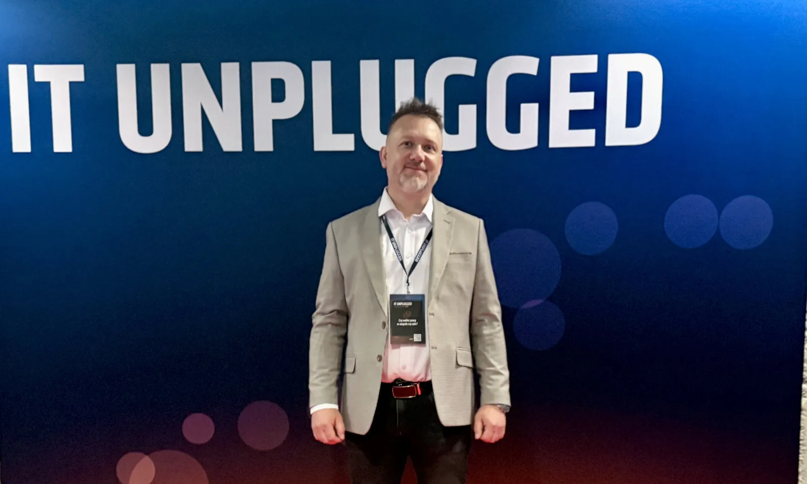 Piotr Kruk na tle ścianki konferencji IT Unplugged w Lublinie
