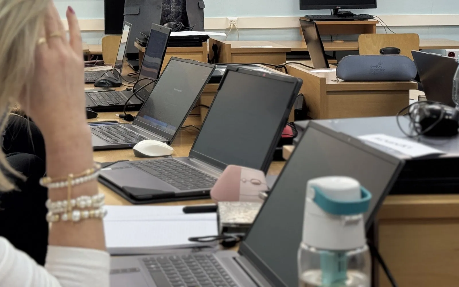 Stanowiska uczestników szkolenia: otwarte laptopy, notatniki i długopisy na ławkach w sali komputerowej