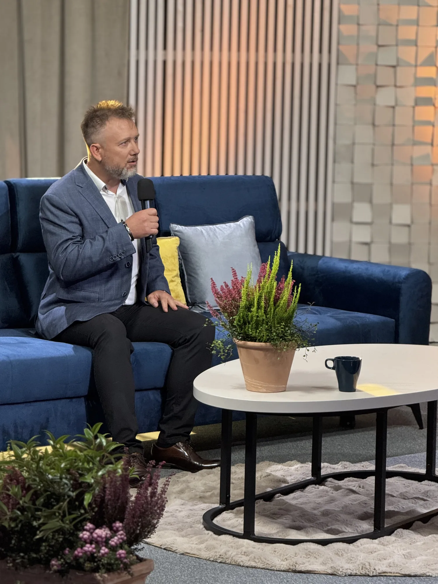 Piotr Kruk z mikrofonem podczas nagrania w studiu telewizyjnym