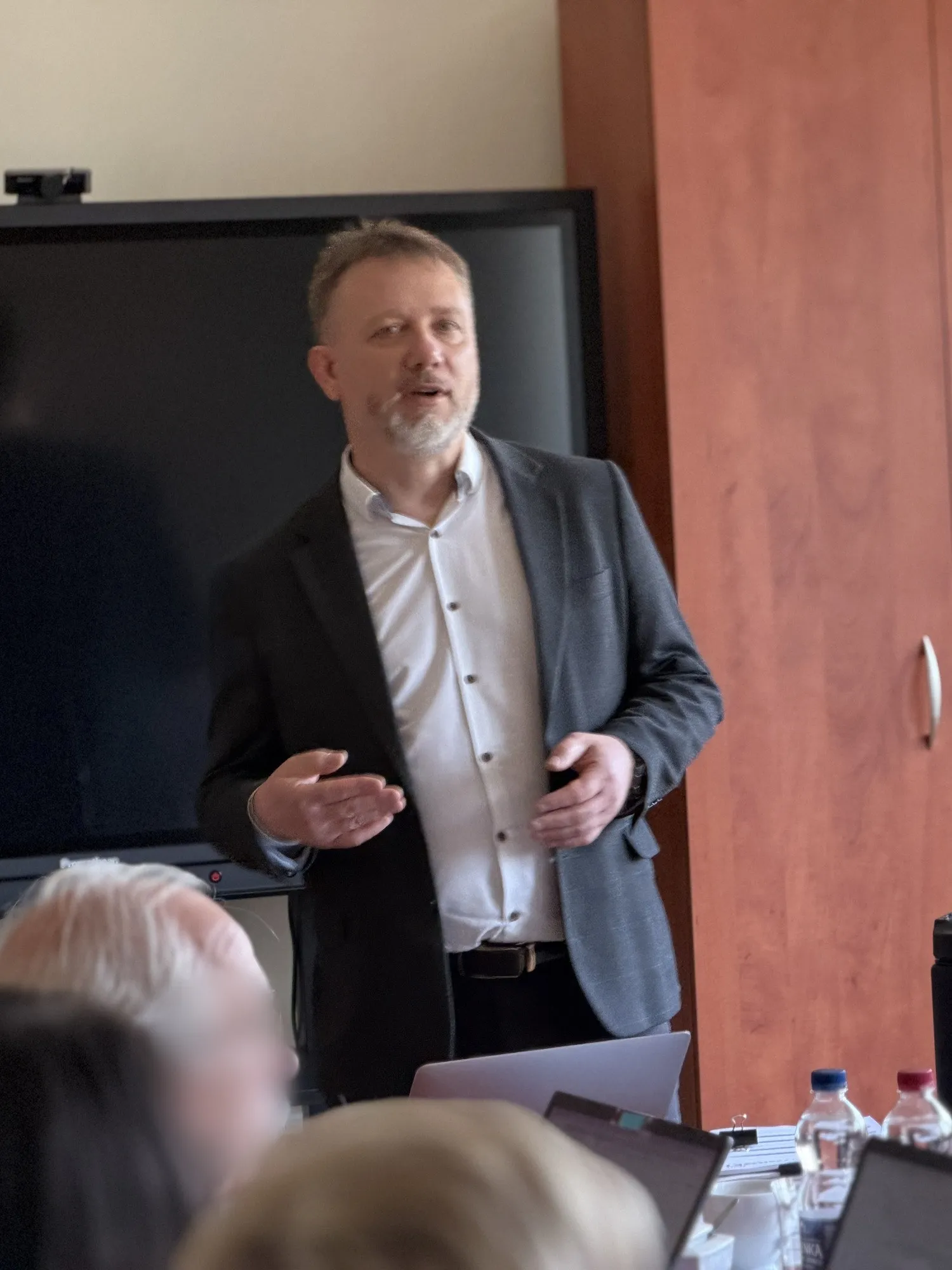 Piotr Kruk podczas szkolenia dla dyrektorów; uczestnicy przy stołach z dokumentami