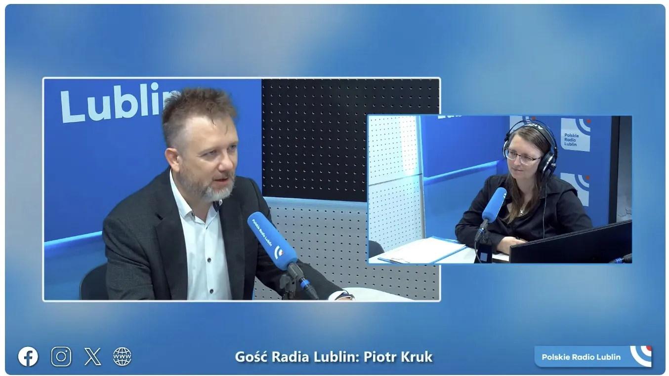Piotr Kruk w studiu Polskiego Radia Lublin, przy mikrofonie, w rozmowie z prowadzącą; na ekranie podpis „Gość Radia Lublin: Piotr Kruk”