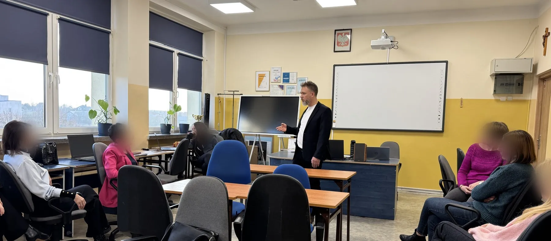 Warsztat dla zespołu szkoły w sali komputerowej — nauczycielki siedzą przy stanowiskach, Piotr Kruk mówi przy tablicy
