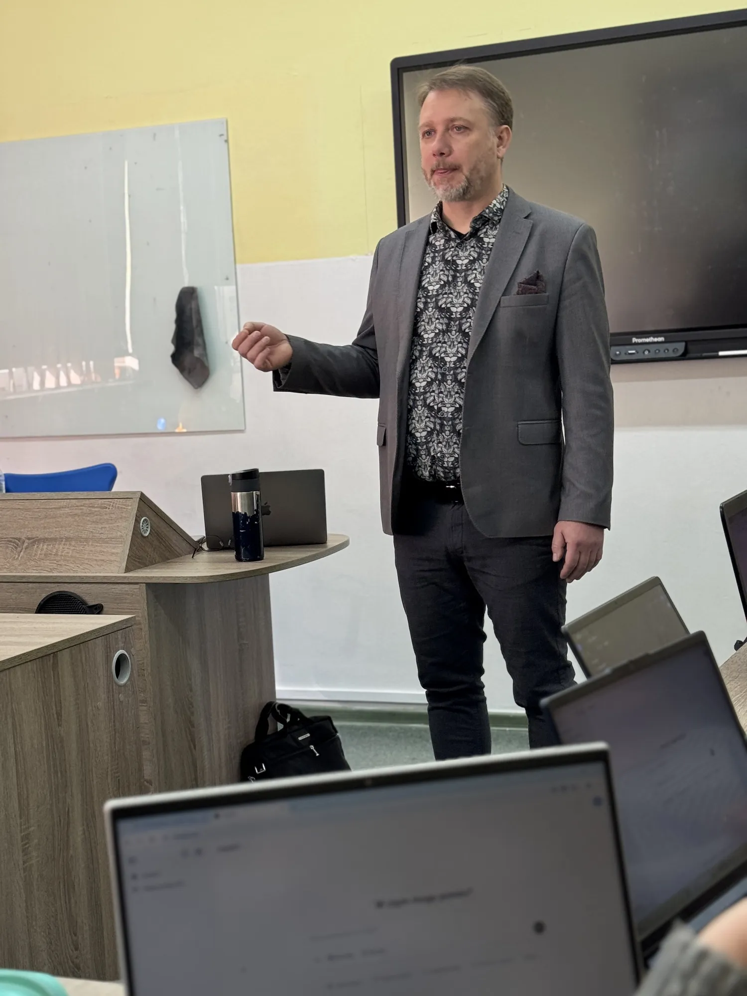 Piotr Kruk podczas warsztatu w szkolnej sali komputerowej wskazuje na tablicę