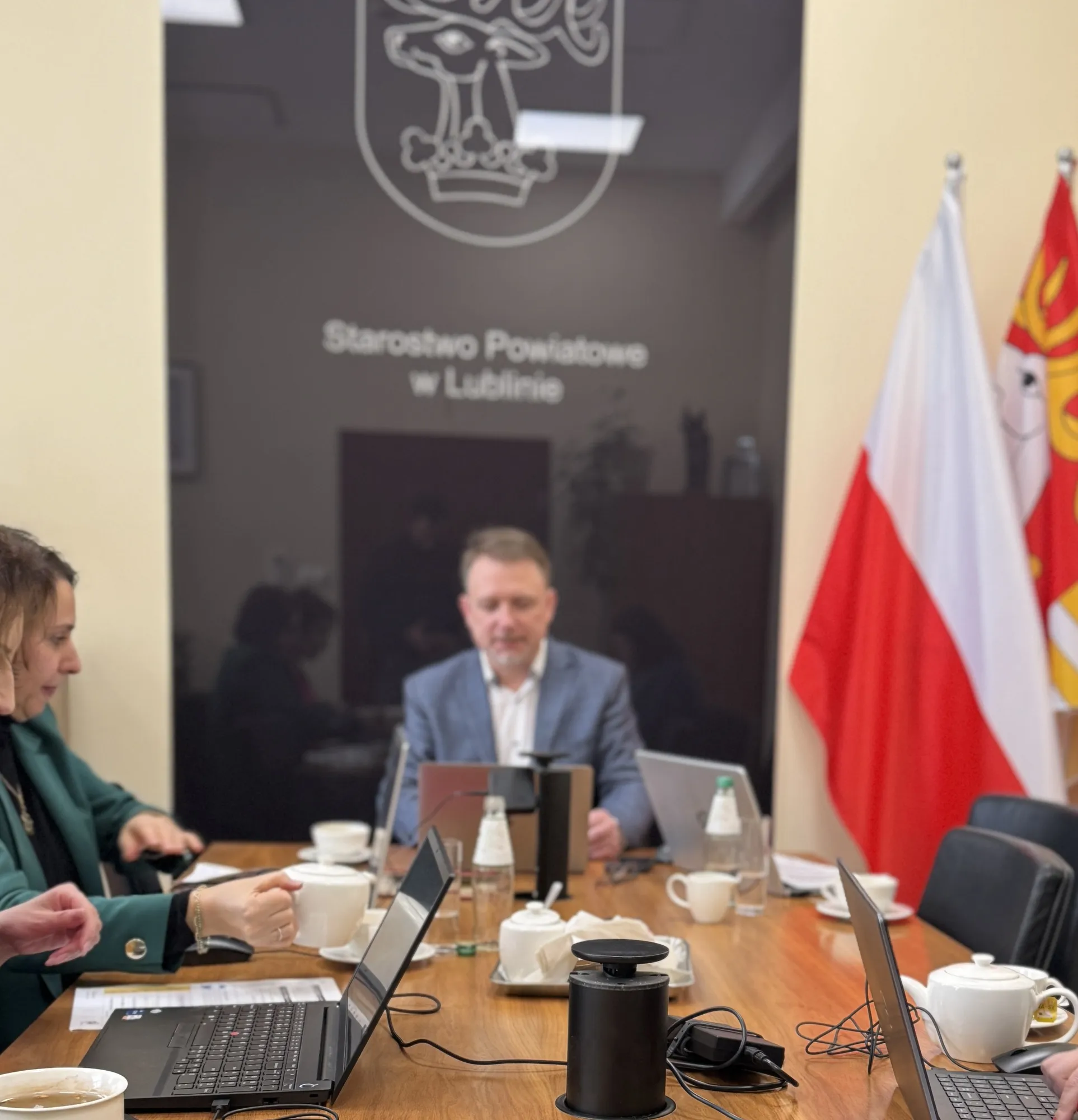 Warsztat w sali konferencyjnej Starostwa Powiatowego w Lublinie — uczestnicy pracują przy laptopach, Piotr Kruk prowadzi zajęcia u szczytu stołu